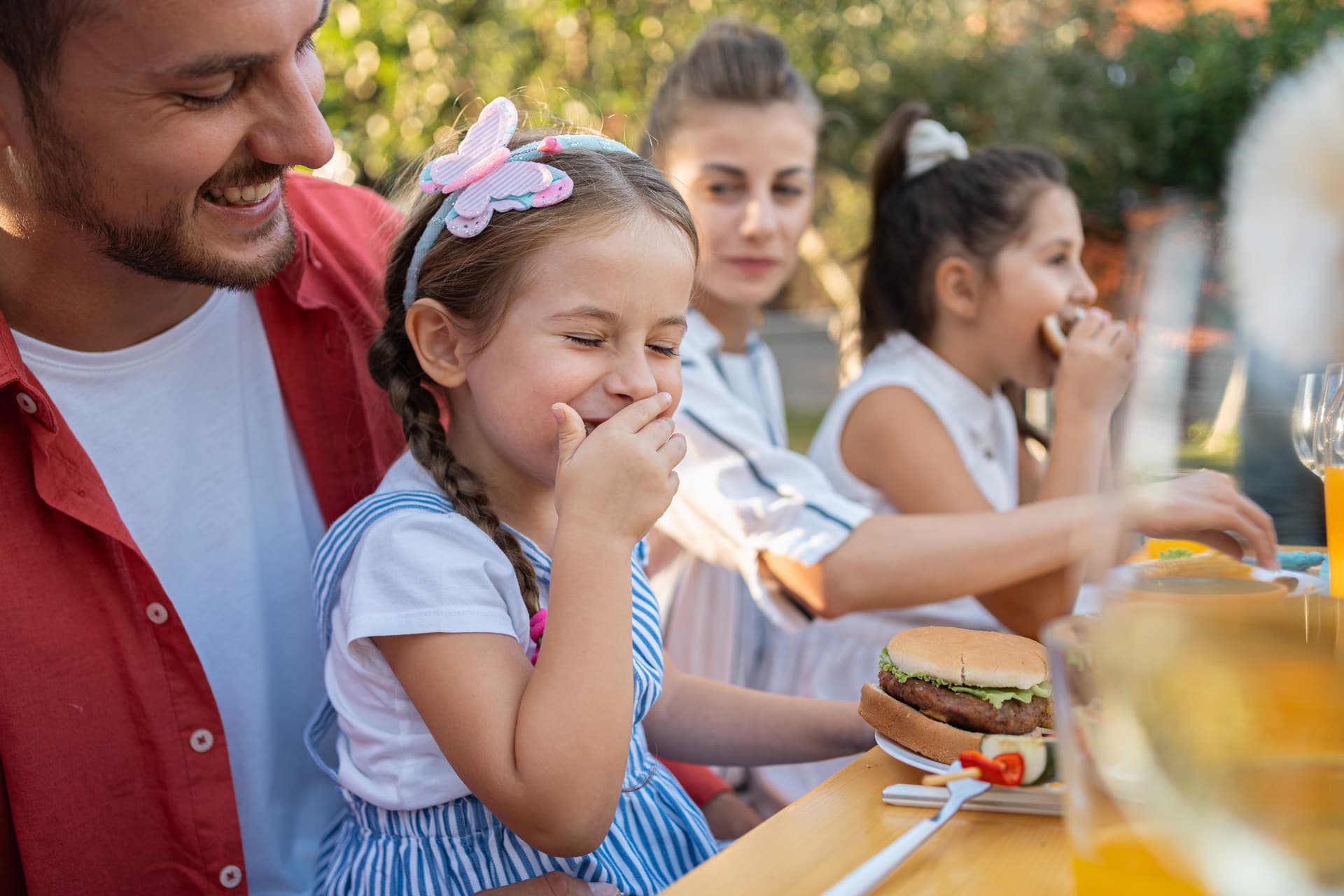 A child laughing while eating a burger.